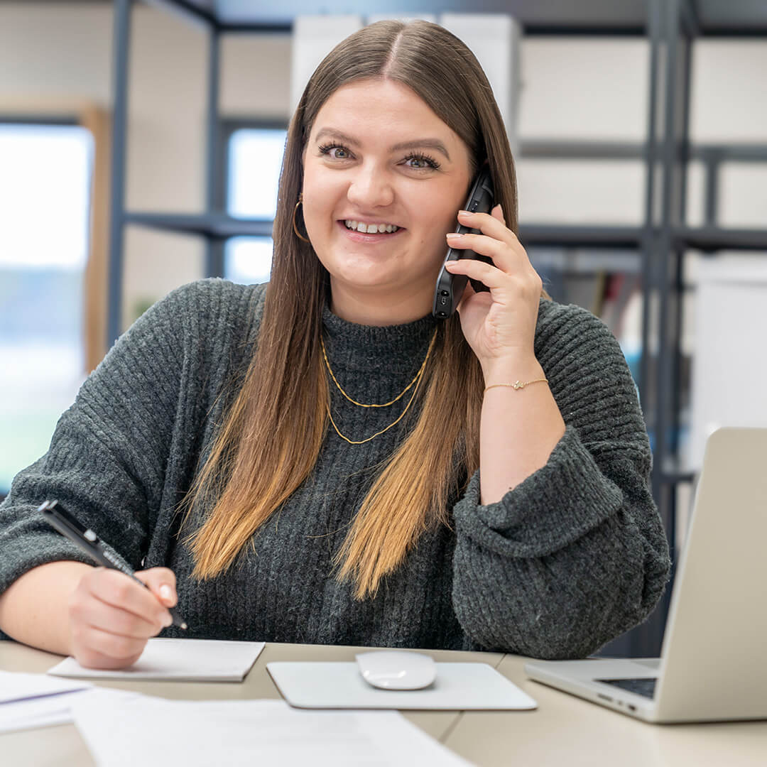 Mitarbeiterin führt ein freundliches Gespräch am Telefon